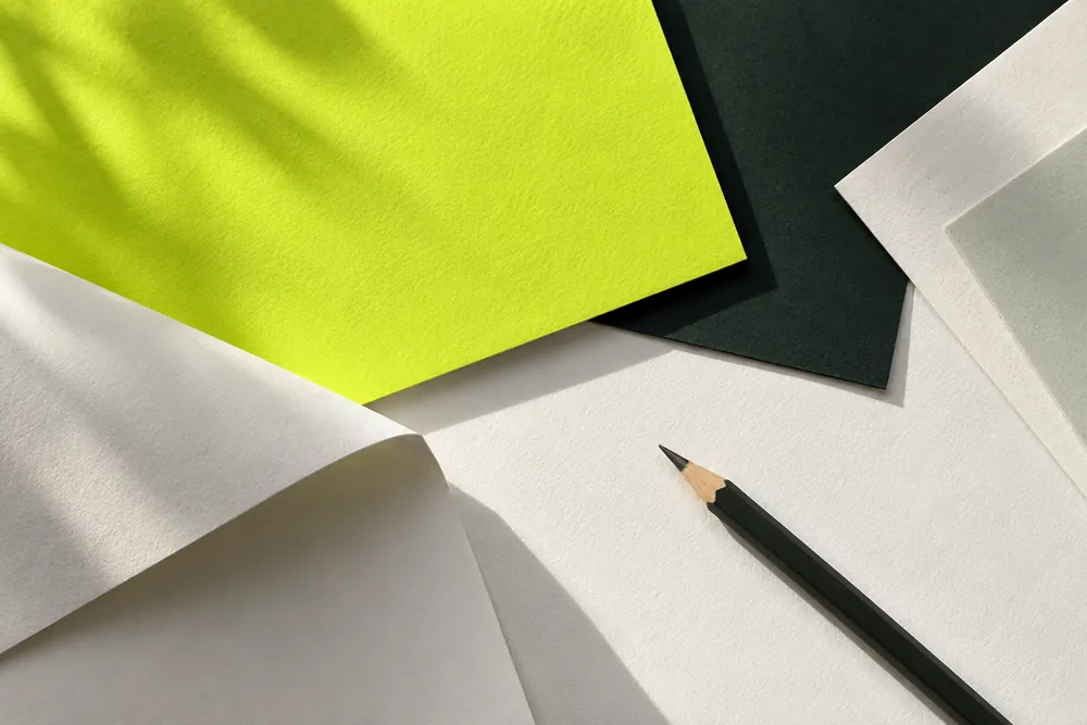 Limegröna och mörka designpapper med en blyertspenna.